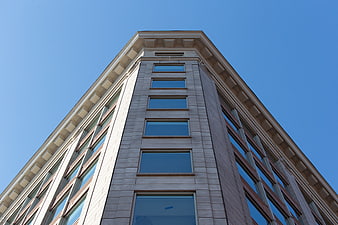 Low angle view of modern office building facade against blue sky