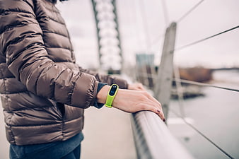 Person wearing fitness tracker on bridge railing