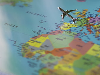 Miniature Airplane Model Positioned Over Colorful World Map