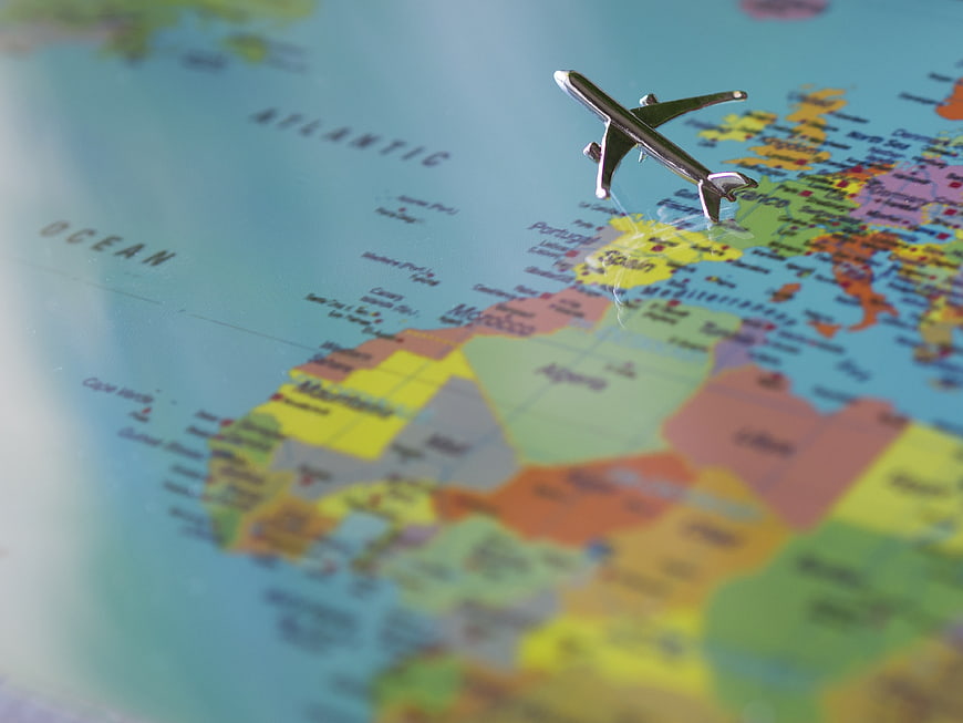 Miniature Airplane Model Positioned Over Colorful World Map