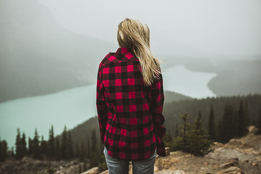 Woman in Red Plaid Shirt Looking at Misty Mountain Lake