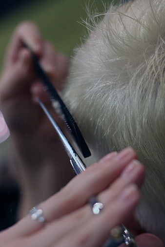 Close up of hairdresser cutting blonde hair with scissors