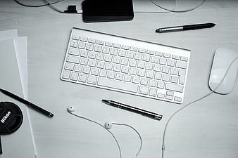 Minimalist white workspace with keyboard, mouse, and pens