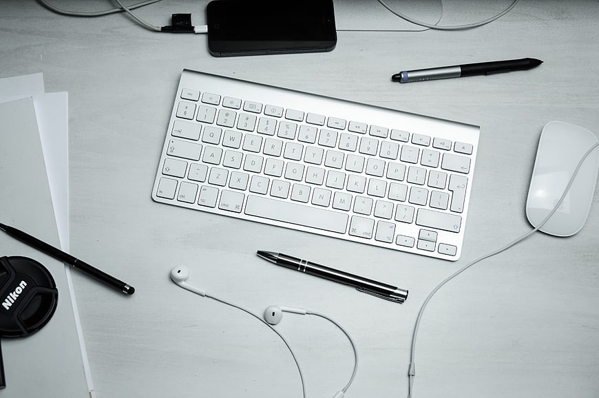 Minimalist white workspace with keyboard, mouse, and pens