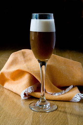 Glass of dark beer with foam on wooden table