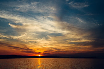 Dramatic Sunset Over Lake with Golden Clouds and Silhouette