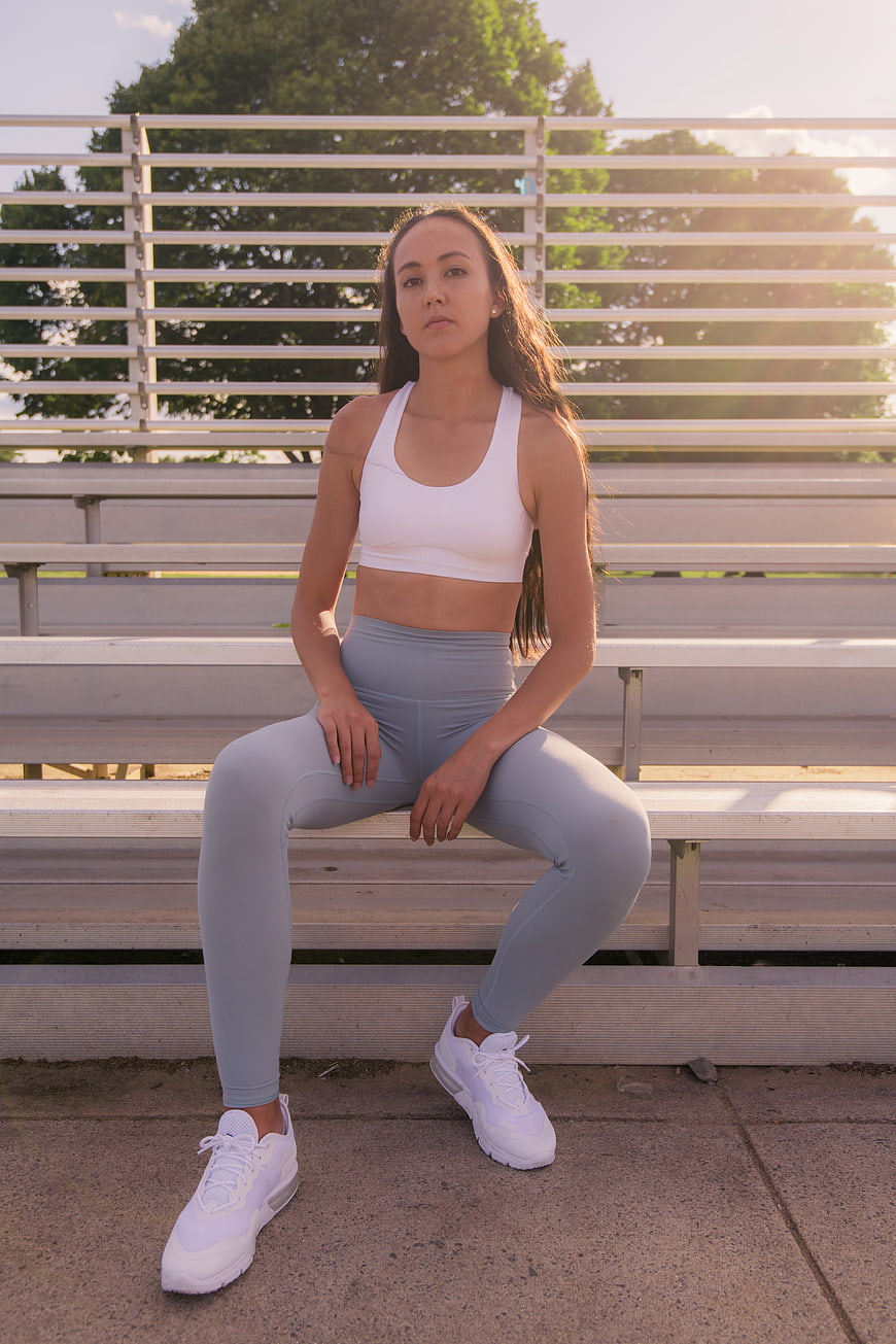 Young woman in white sportswear sitting on bleachers