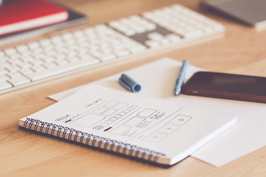 UX Wireframe Sketch on Desk with Keyboard and Smartphone