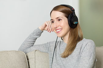 Happy Woman Listening to Music with Headphones on Sofa