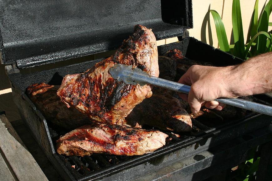 Hand Turning Large Grilled Steak on Outdoor Charcoal Grill