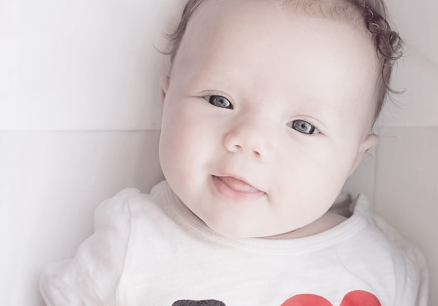 Close-up portrait of a smiling baby with blue eyes