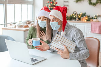 Couple in Santa Hats and Face Masks Video Calling for Christmas