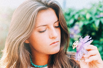 Young woman smelling purple passion flower outdoors