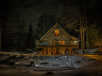 Cozy wooden cabin with warm lights in snowy winter night