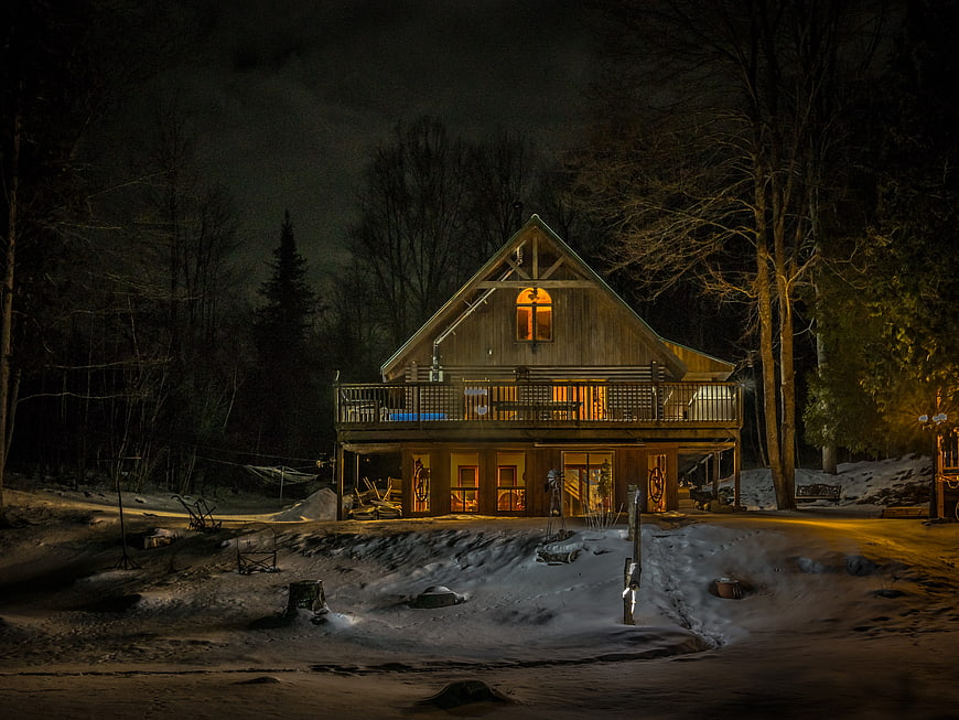 Cozy wooden cabin with warm lights in snowy winter night