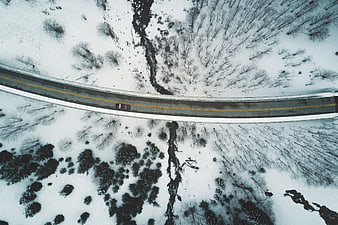 Aerial View of Winding Road Through Snowy Winter Forest