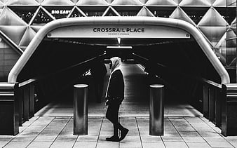 Black and white photo of person walking through Crossrail Place tunnel