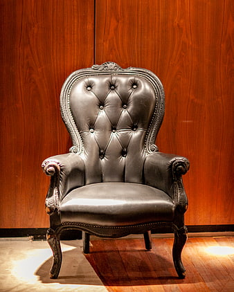 Vintage Black Leather Armchair Against Wood Wall