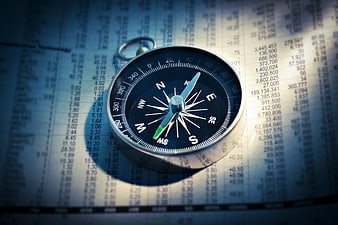 Compass on Financial Newspaper with Stock Market Data