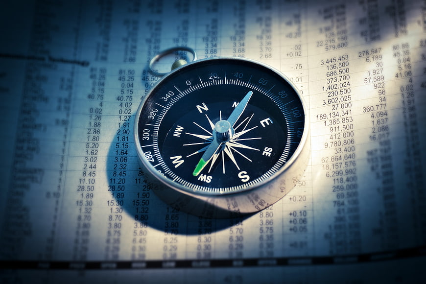 Compass on Financial Newspaper with Stock Market Data