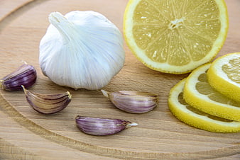 Fresh garlic bulb and sliced lemon on wooden board
