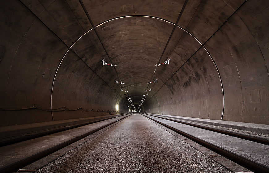 Perspective view of empty concrete tunnel with railway tracks