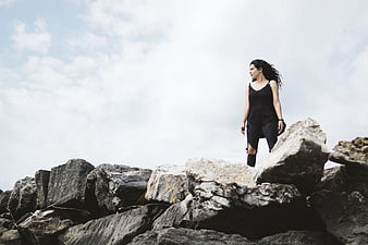 Woman standing on rocky cliff edge looking out at sky