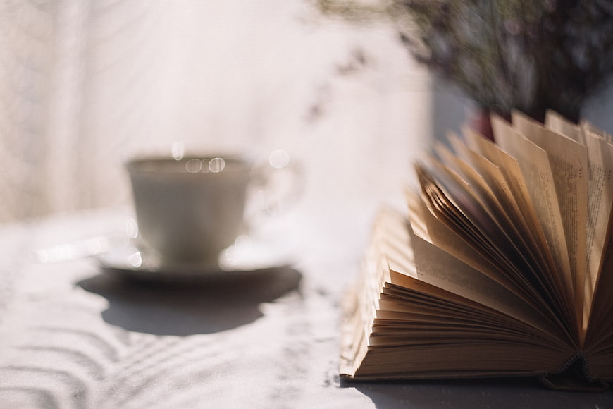 Open vintage book and blurred coffee cup on table