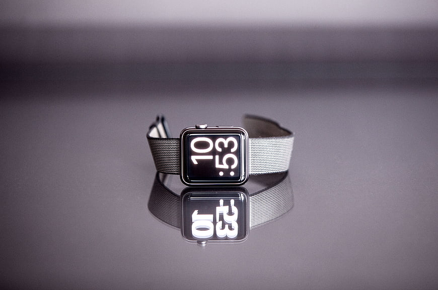 Silver smartwatch with Milanese loop on reflective surface