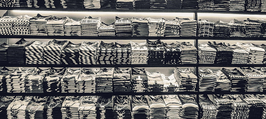 Black and white shelves of folded t-shirts in a clothing store