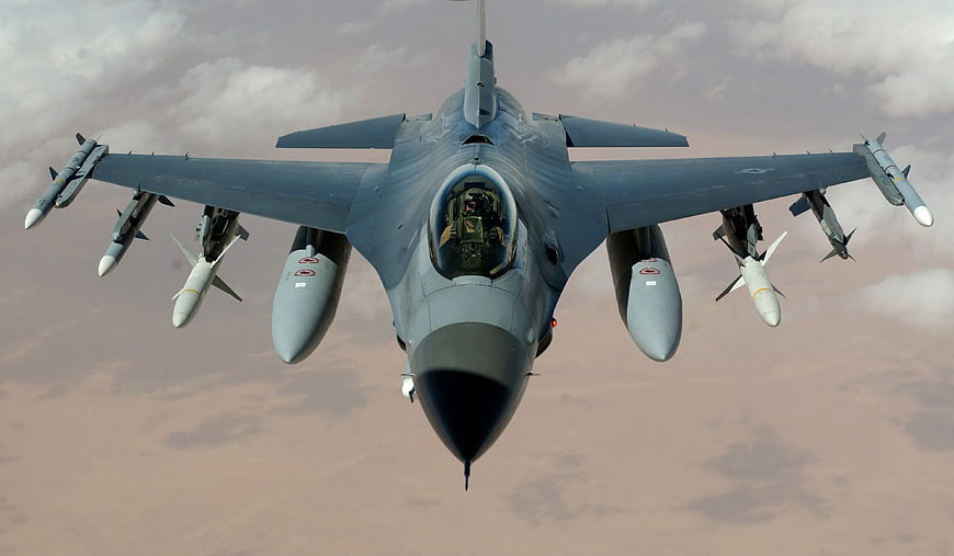 Front view of grey fighter jet with missiles in flight