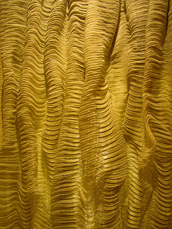 Golden pleated fabric texture with shiny metallic folds and abstract pattern