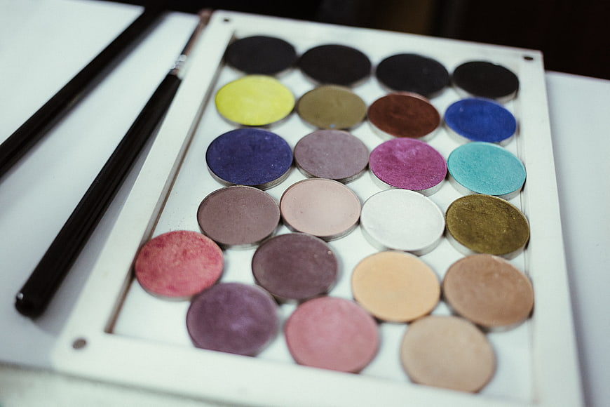 Colorful makeup palette with brushes on white background