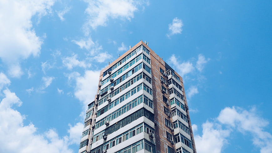 Low angle view of tall apartment building against blue sky