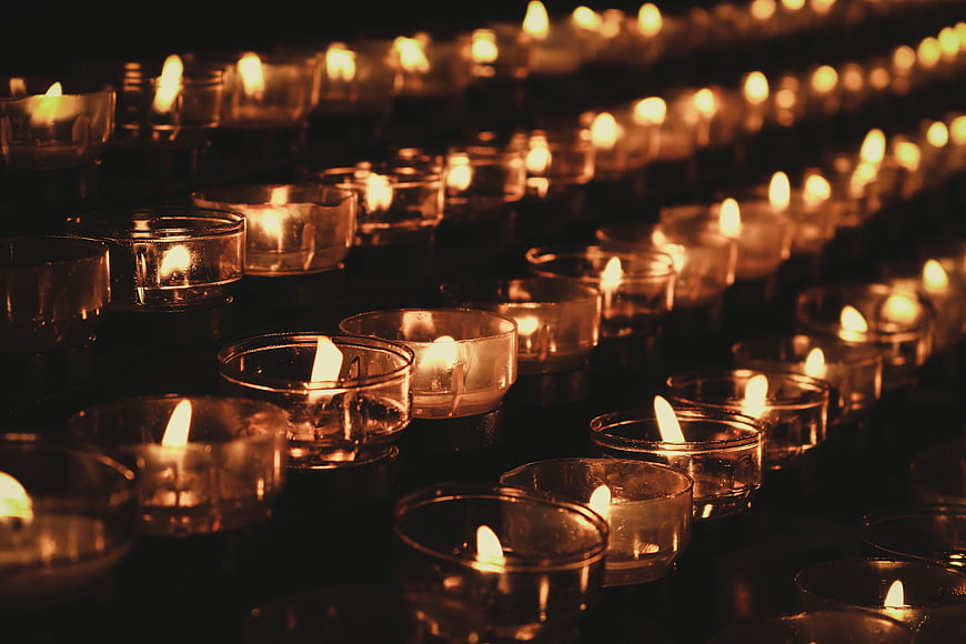 Rows of lit tea light candles in glass holders