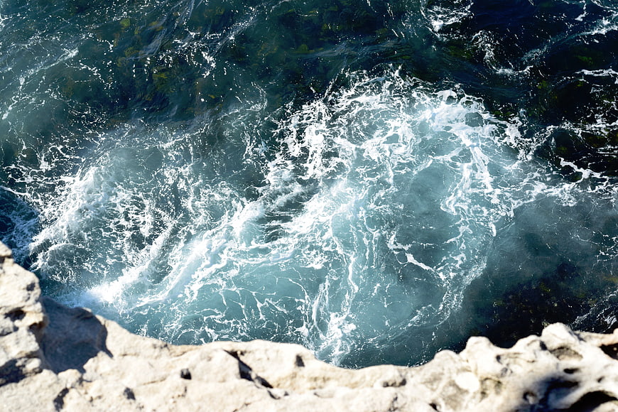 Aerial view of crashing ocean waves against rocky coastline