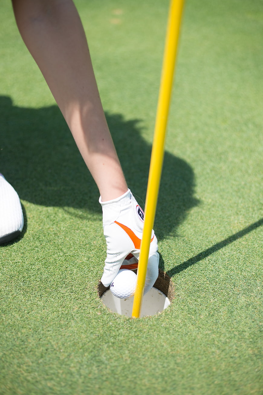 Golfer Retrieving Ball from Hole on Green
