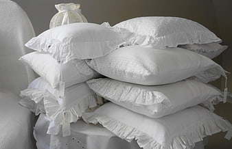 Stack of white ruffled pillows with lace details