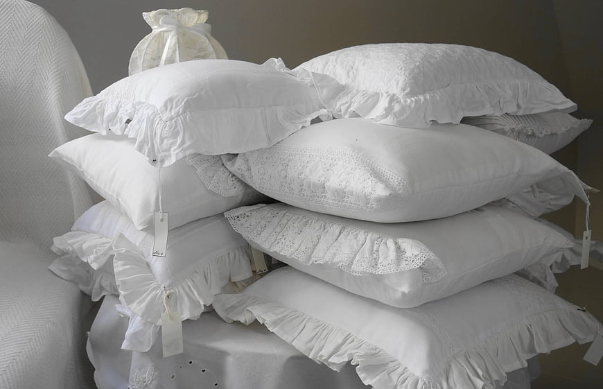 Stack of white ruffled pillows with lace details