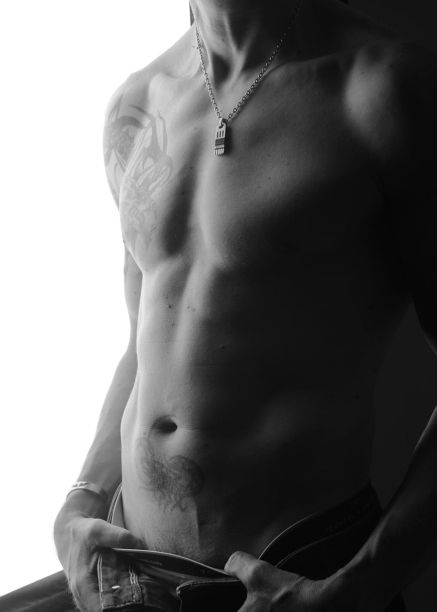 Black and white photo of a muscular tattooed male torso