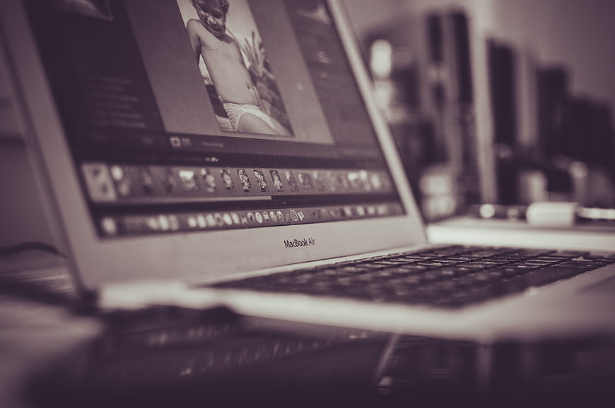 Close-up of MacBook Air displaying photo editing software on a desk