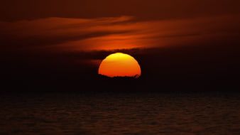 Dramatic orange sunset over dark ocean horizon