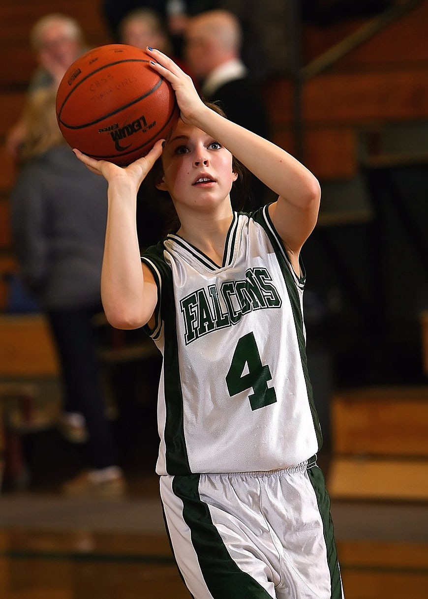 Teenage female basketball player shooting a free throw in a gymnasium