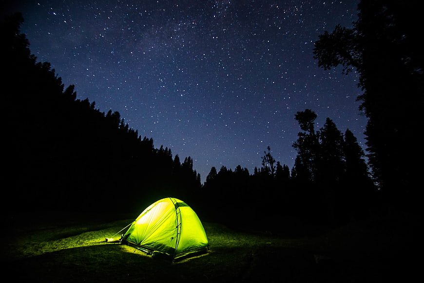 Glowing Tent Under Starry Night Sky in Forest