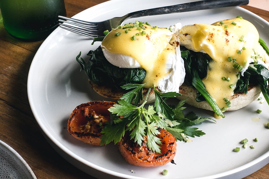 Eggs Benedict with Spinach and Roasted Tomatoes on White Plate