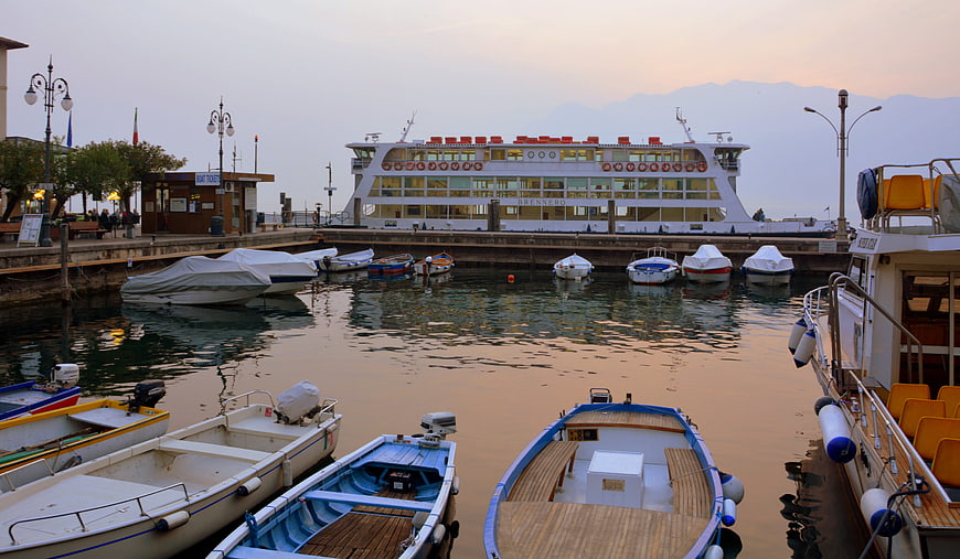 Boats docked in harbor at sunset with ferry and mountains