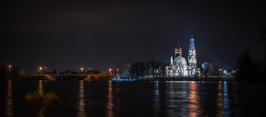 Illuminated Orthodox Church at Night with River Reflections