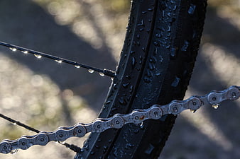 Close-up of wet bicycle chain and tire with water droplets