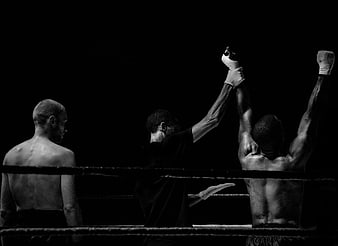 Boxing referee raises winner's hand in black and white