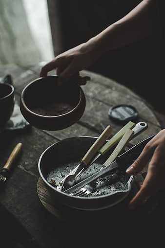 Hands clearing dirty dishes from rustic wooden table